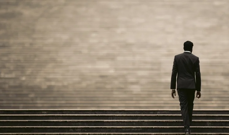 a young Indian man walking up steps 