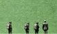 some men with rucksacks against a green background